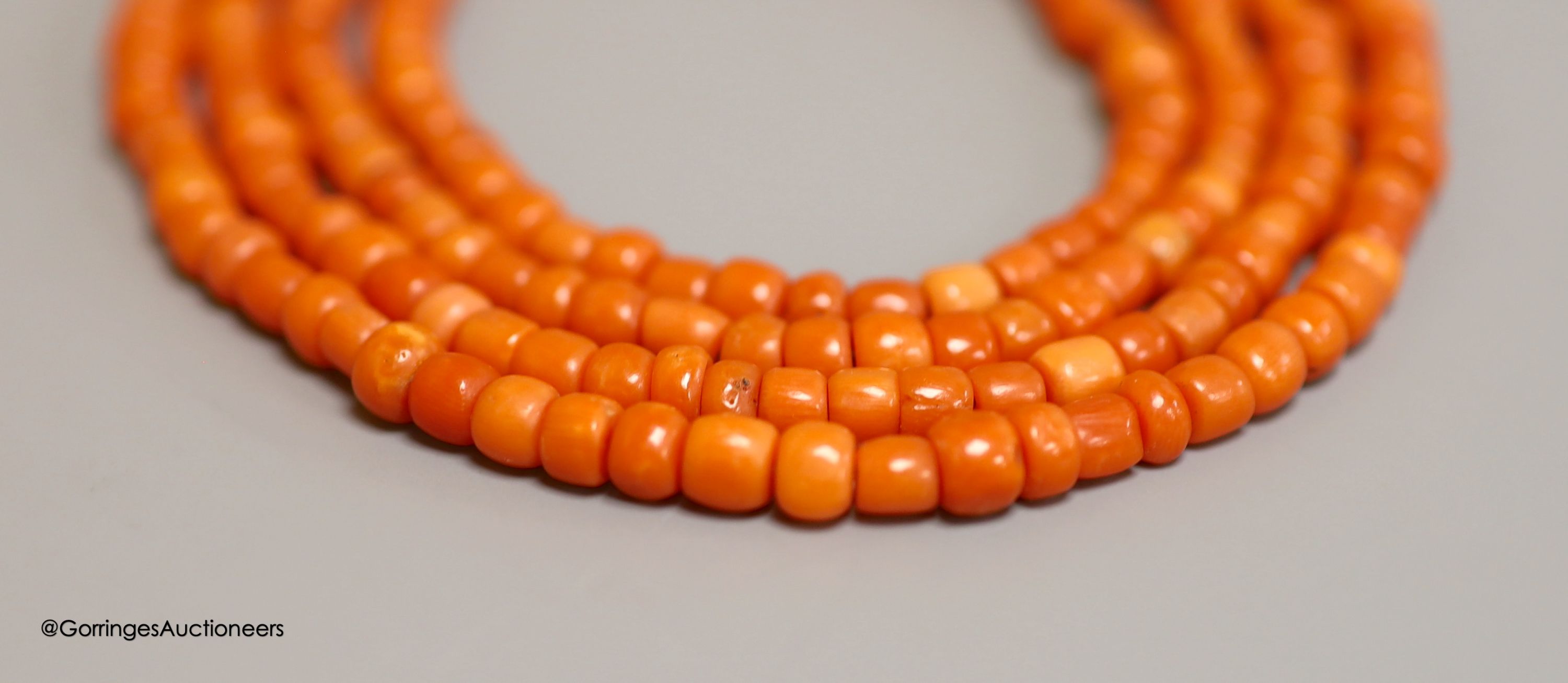 A long single strand coral bead necklace, with paste set clasp, 144cm, gross 55 grams.